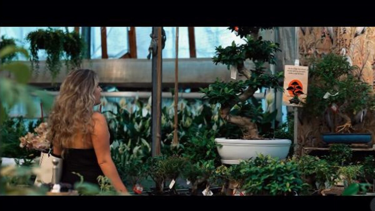 Woman walking through a lush garden centre in a cinematic frame